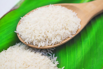 Thai jasmine rice on green leaf and wooden spoon top view background with copy space 