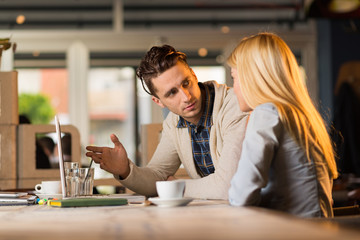 Two business colleagues working in a cafe and using laptop