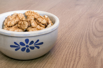 Walnut kernels in a gray bowl on a wooden table. Healthy food. Place for text.