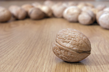 Many walnuts in shell on the table. One walnut close-up against the background of other nuts. Healthy food. Place for text.