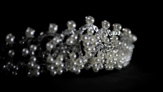 Close-up image of wedding diamond and pearl crown in luxury jewelry shop rotating on black background.
