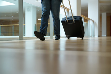 Fototapeta premium Closeup of traveller pulling suitcase in airport corridor