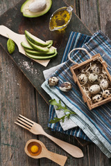 Quail eggs, avocado and other ingredients for spring salad. Dietary healthy food on rustic wooden background. Close-up, top view