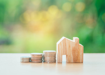 Coin money and house model on table and green background. Finance and banking concept.