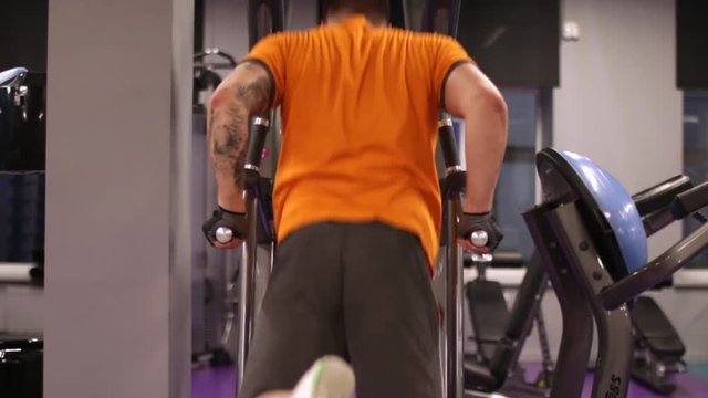 A man doing triceps dip exercise on parallel bars in gym