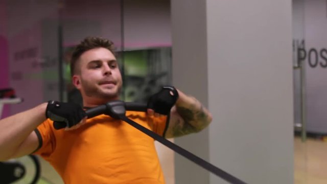 A tattooed man exercising on rowing machine