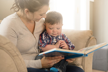 Mother reading book with her child on sofa