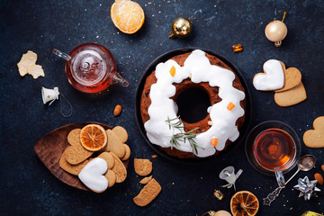 Traditional christmas cake with dried fruits soaked in rum and sugar glaze. Teatime with heart-shaped ginger cookies. Christmas background with festive decoration. Horizontal composition