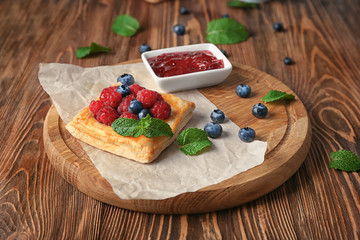 Wooden board with yummy berry puff pastry on table