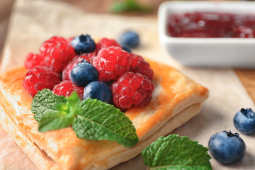 Yummy puff pastry with berries on table