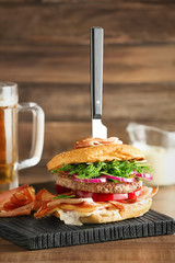 Tasty burger with prosciutto on wooden board