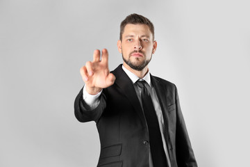 Stock exchange broker pushing button on virtual screen against light background
