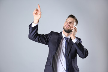 Stock exchange broker pushing button on virtual screen and talking by phone against light background