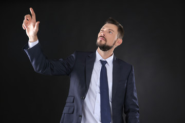 Stock exchange broker pushing button on virtual screen against dark background