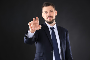 Stock exchange broker pushing button on virtual screen against dark background