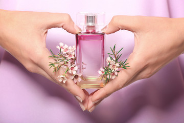 Hands of young woman with bottle of floral perfume, closeup