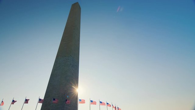 The sun appears because of the Washington monument. American flags flap below