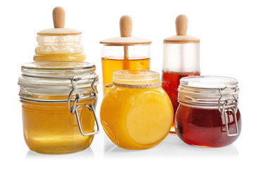 Jars with aromatic honey on white background