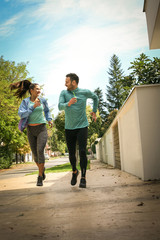 Fototapeta na wymiar Young couple running together on sidewalk. Healthy lifestyle.