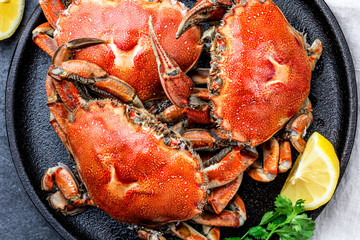 Cooked whole crabs on black plate served with white wine, black slate background, top view © lblinova