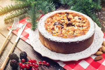 Homemade Christmas or New Year holiday berry pie with nuts on wooden table background. Concept of festive desserts