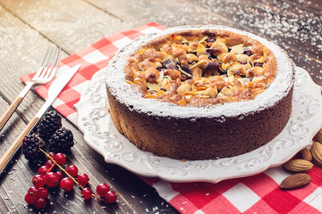 Homemade Christmas or New Year holiday berry pie with nuts on wooden table background. Concept of festive desserts