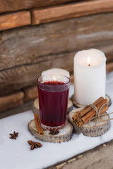 mulled wine on a wooden stand white candles bundle of dry cinnamon sticks on the table with the snow