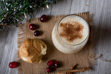 Top view of egg nog with a cream puff and cranberries