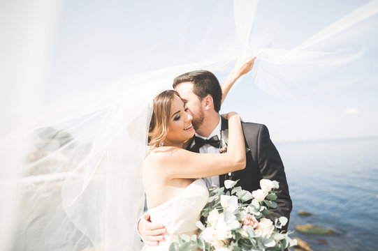 Happy and romantic scene of just married young wedding couple posing on beautiful beach