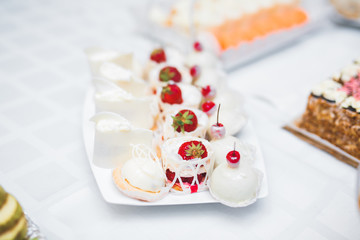 Delicious and tasty dessert table with cupcakes shots at reception closeup