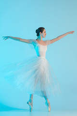 Young and incredibly beautiful ballerina is dancing in a blue studio
