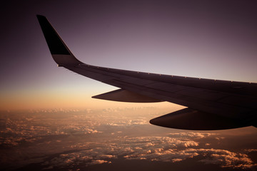 Fototapeta premium Beautiful sunset with wing of airplane with beautiful cloud and blue sky in background. Airplane wing and blue sky with copyspace for text.
