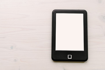 Blank screen of ebook reader on white wooden table