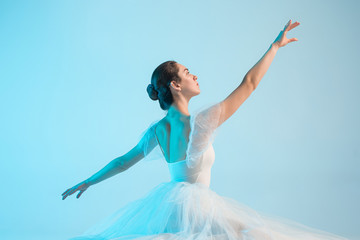 Fototapeta na wymiar Young and incredibly beautiful ballerina is dancing in a blue studio