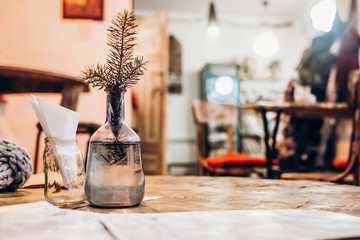 beautiful fir bracn in warm light in glass vase on wooden table in cafe.  winter christmas holidays, space for text