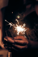 hand holding a burning sparkler firework bengal light. space for text. burning sparkler closeup in...