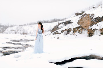 Beautiful Woman in a Luxury Lush Blue Dress. Fantastic Shot, Fairytale Princess is Walking in the Winter Forest. Fashionable Toning, Creative Film Colors