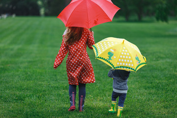 Mother and son walking in the rain with colorful umbrellas