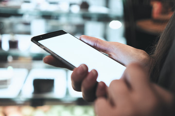 The girl is holding the phone in her hands. Blurred background storefront