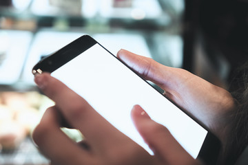The girl is holding the phone in her hands. Blurred background storefront