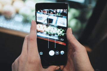 The girl is taking pictures on the phone. Shop window. Green apples