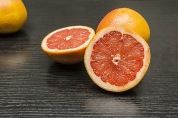 Ripe pink grapefruit cut in half on a wooden table.