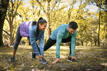 Young couple stretching before running in city park. On the move.