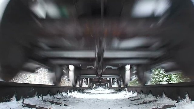 Under the moving train. To see  speeding freight echelon from the bottom. Commodity Express  moves in winter foresr. Multi-train with tank of oil  and gas on the North road. 