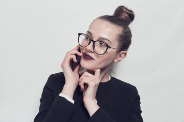 The girl in a business suit. Black glasses. He talks on the phone. On a white background