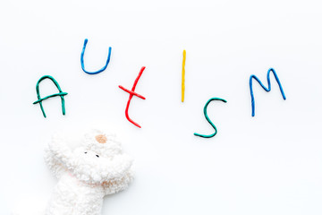 Childhood diseases. Word autism near toys on white background top view