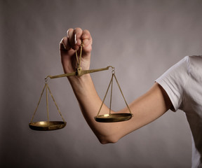 young woman holding a justice scale on a gray background