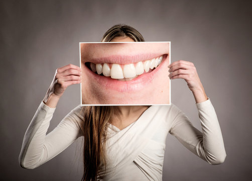 young woman holding a picture of a mouth smiling