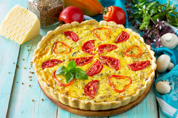 A classic quiche Lorraine pie with buckwheat, mushrooms, paprika, tomatoes, cheese and egg filling on a wooden table. Copy space.