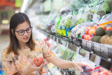 Woman in a supermarket at the shelf for fruits shopping